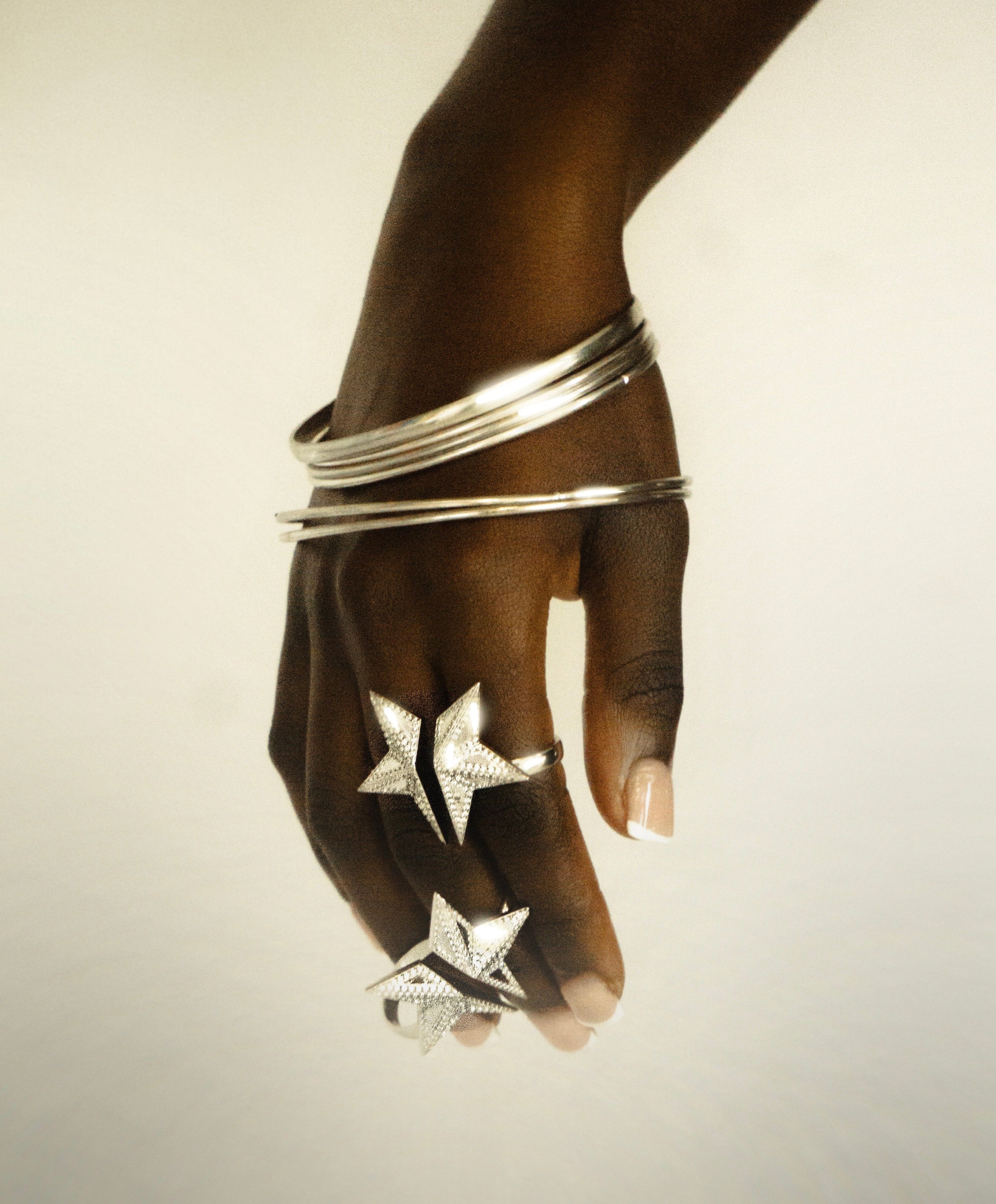 A hand wearing multiple silver star-shaped rings and stacked silver bangles, photographed against a plain light background with the text 'THE STAR JO DESIGNS jewellery' at the bottom.
